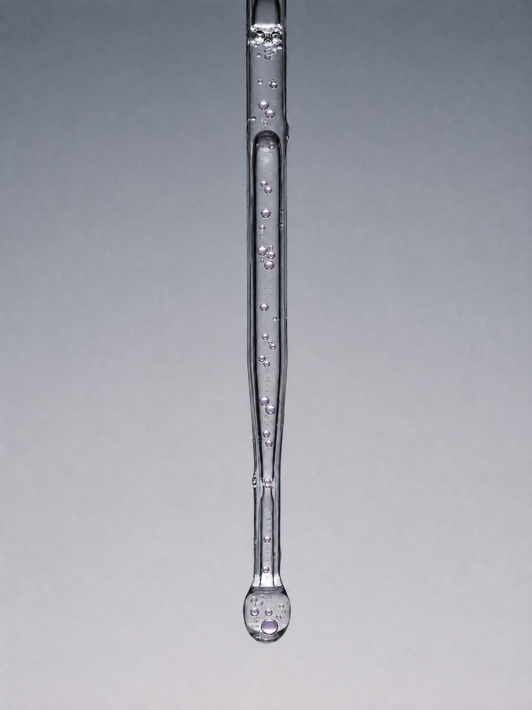 A clear droplet at the end of a glass pipette — concept artwork