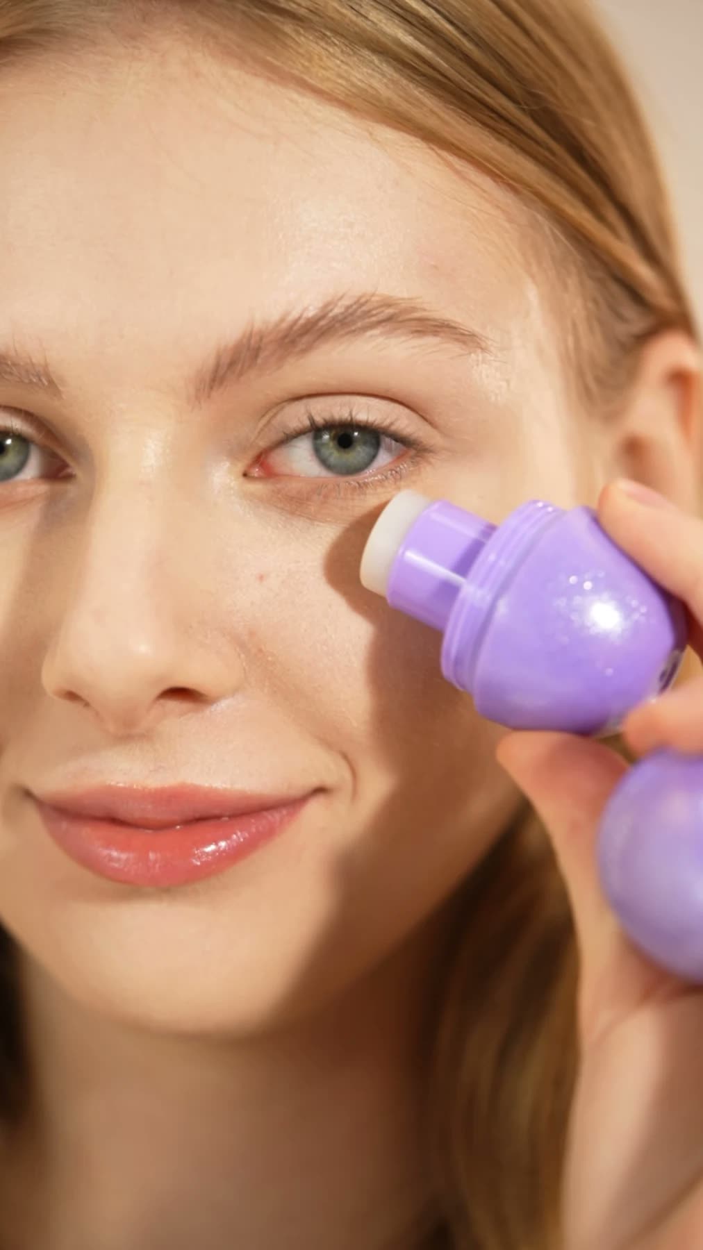 Model gliding the Rose PDRN Firming Balm Stick under her eye
